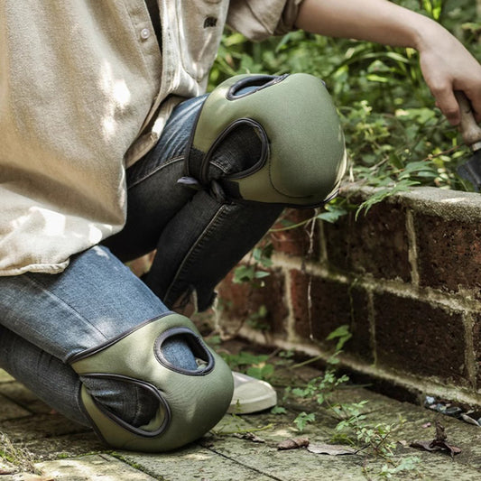 Person wearing green knee pads on a brick path with grass in the background