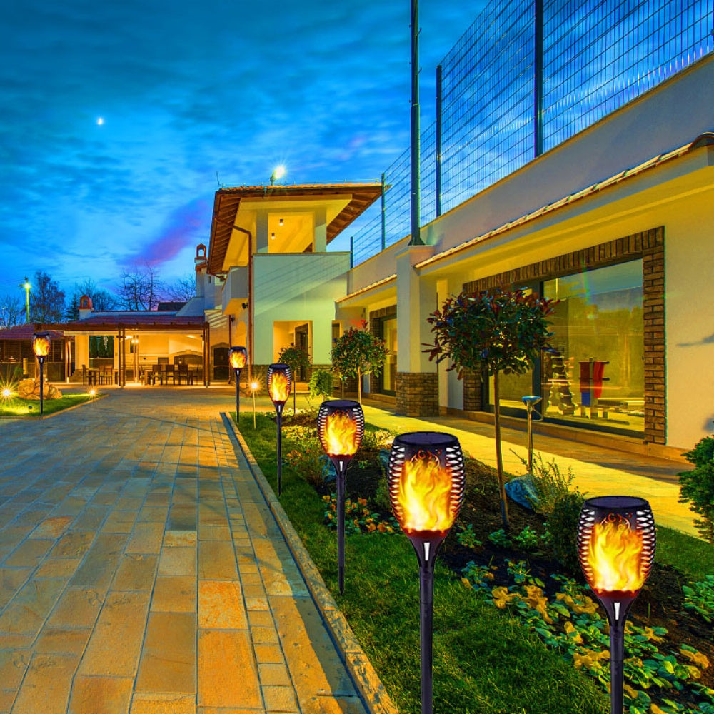 Decorative outdoor lights along a pathway in front of a house at night.