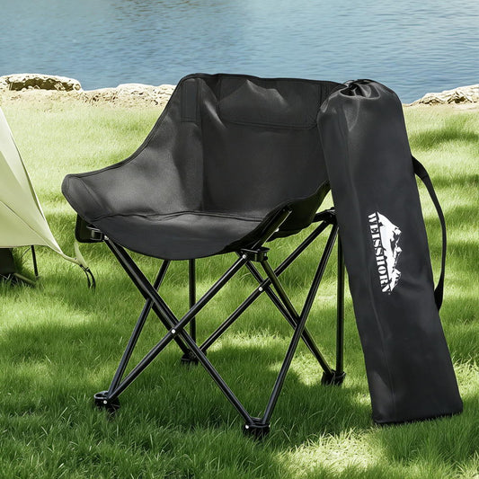 Black folding chair with carrying bag on grass near water