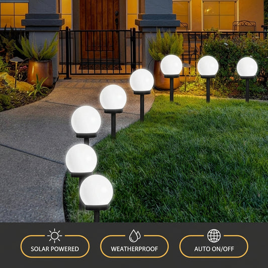 Glowing spherical garden lights on grass next to a pathway
